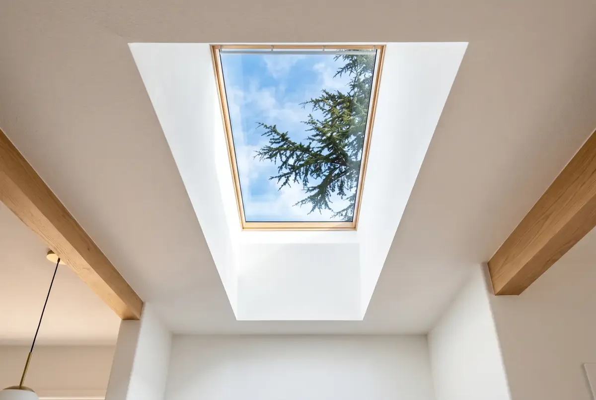 Interior view looking up through a clean skylight to blue sky