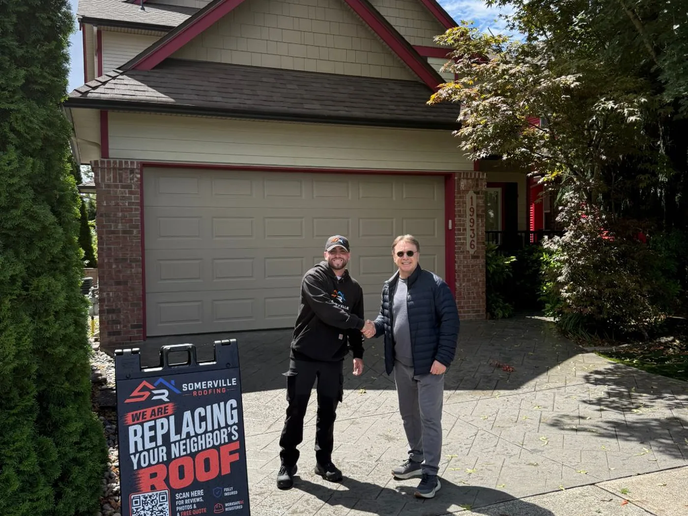 James shaking hands with a homeowner in front of a Somerville Roofing sign on a completed job