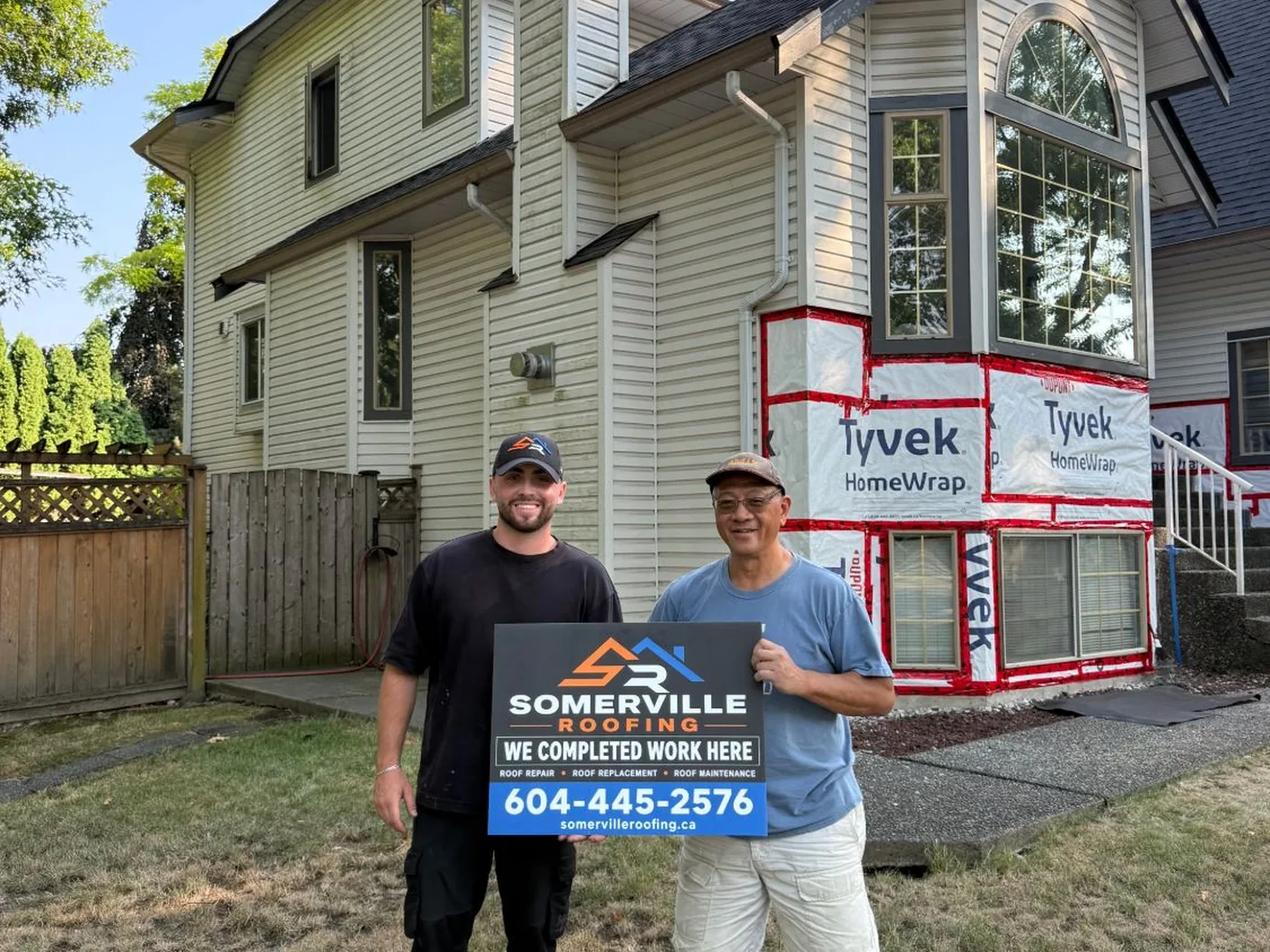 Homeowner with a Somerville Roofing completed-work sign outside their home